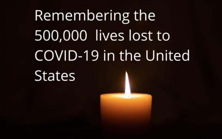 lit candle on a black backdrop, with white text that says "remembering the 500,000 lives lost to COVID-19 in the United States"